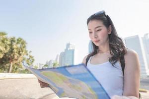 hermosa mujer turista asiática mirando el mapa en busca de turistas lugares turísticos. viajes de vacaciones en verano. foto