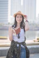 Beautiful asian solo tourist woman smiling and searching for tourists sightseeing spot. Vacation travel in summer photo
