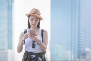 hermosa mujer asiática turista en solitario sonriendo y mirando el teléfono móvil para buscar turistas lugares turísticos. viajes de vacaciones en verano foto