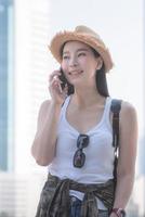 Beautiful asian solo tourist woman smiling and enjoy taking via mobile phone in city downtown. Vacation travel in summer. photo