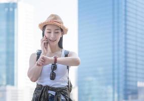 hermosa mujer asiática turista en solitario sonriendo y disfruta hablando por teléfono móvil en el centro de la ciudad. viajes de vacaciones en verano. foto