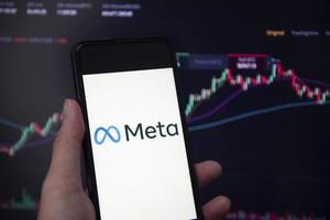 META logo on smartphone screen with hand hold and crypto currency or stocks graph charge trading screen on background. New facebook company logo meta metaverse. Bangkok Thailand, December 2, 2021 photo