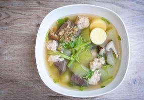 Clear soup blood pork thai healthy food asian on dark background, Tofu Soup bolw with winter melon vegetable eggs tofu slice meat ball and minced pork with celery, top view photo