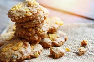 Galletas con chispas de chocolate en el fondo de la tabla de saco, cerca de copos de maíz de galleta foto