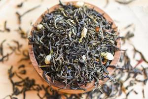 Chinese dry tea on wooden bowl, jasmine tea dried for brew tea, leaf black tea photo