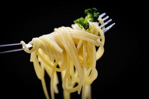 Spaghetti on fork and black background - spaghetti italian pasta with parsley in the restaurant italian food and menu concept photo