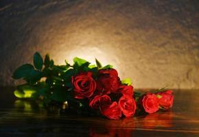 Red roses flower bouquet on rustic wood and candlelight background - flowers rose petals romantic love valentine day concept photo