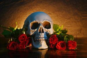 Ramo de flores de rosas rojas en madera rústica con fondo de calavera y velas - flores rosa amor romántico y muerte concepto de día de San Valentín foto