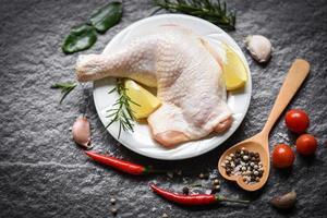 Raw chicken leg on white plate for cooking thai asian food rosemary chicken lemon on wooden food table photo