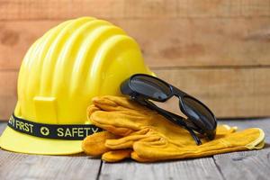 Safety equipment standard construction safety - Industrial protective workwear tool with yellow hat safety helmet glasses and gloves on wood background photo