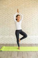 Latin woman practicing yoga on mat photo