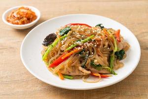 japchae or stir-fried Korean vermicelli noodles with vegetables and pork topped with white sesame photo