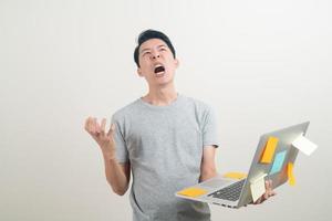 young Asian man holding laptop with stress face or working hard photo