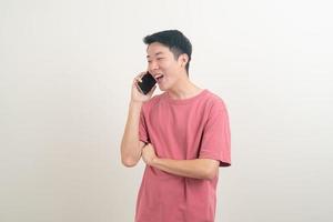 Joven asiático usando o hablando teléfono inteligente y teléfono móvil con cara feliz foto