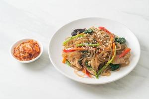 japchae or stir-fried Korean vermicelli noodles with vegetables and pork topped with white sesame photo