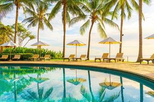 Beautiful luxury umbrella and chair around outdoor swimming pool in hotel and resort with coconut palm tree on sunset  or sunrise sky photo