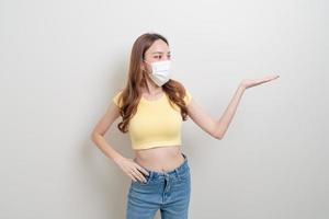 portrait beautiful woman wearing mask with hand presenting or pointing photo