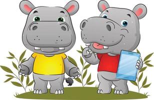 The couple of the hippopotamus is holding the tablet and explaining something in the garden vector