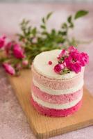 un pequeño pastel blanco y rosa decorado con flores y bayas