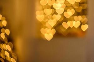 A lot of golden lights in the shape of hearts in the defocus on a dark background photo