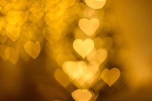 A lot of golden lights in the shape of hearts in the defocus on a dark background photo