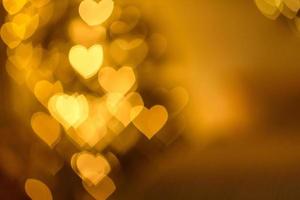 A lot of golden lights in the shape of hearts in the defocus on a dark background photo