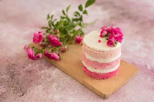 A small cake of white and pink decorated with flowers and berries photo