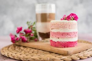 A small cake of white and pink decorated with flowers and berries photo