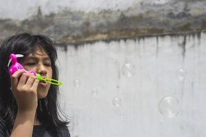 A girl holding a bubble maker and blowing them out.