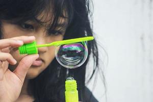 A girl holding a bubble maker and blowing them out. photo