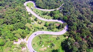 Luftaufnahme von Autos, die durch eine Kurvenstraße auf einem von Grün umgebenen Berg fahren. die Transportstraße über den Berg. video