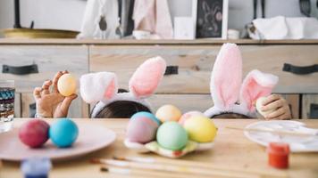 madre con niño orejas de conejo escondido mesa con huevos de colores