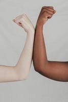 close up fair dark skinned women s hand flexing their fist against grey backdrop photo
