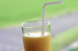 Juice in glass and plastic straws on blur background photo