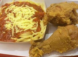 Fresh delicious crispy fried chicken golden brown with red sauce spaghetti on white box. photo