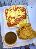 Fresh delicious crispy fried chicken golden brown with red sauce spaghetti on white box. photo