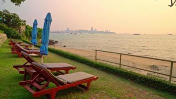 chair pool around swimming pool with sea background at sunset time - holidays and vacation concept video