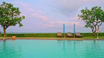 chair pool around swimming pool with sea background at sunset time - holidays and vacation concept video