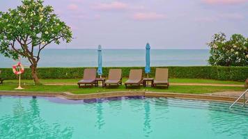 cadeira de piscina ao redor da piscina com fundo do mar na hora do pôr do sol - feriados e conceito de férias video