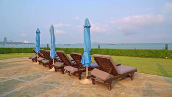 sedia piscina intorno alla piscina con lo sfondo del mare al tramonto - vacanze e concetto di vacanza video