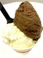 helado de vainilla y patrón de postre helado sabor chocolate en taza negra mano sujetando sobre madera y blanco. foto