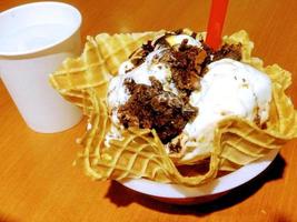 helado de vainilla y patrón de postre helado sabor chocolate en taza de gofre sobre madera. foto