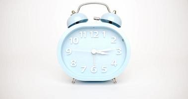 lapso de tempo, o despertador azul mostra a passagem do tempo. no fundo branco. video