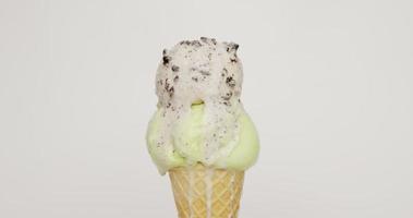de cerca, fusión de dos sabores de helado en un cono. flujo de helado después de derretirse. sobre el fondo blanco.