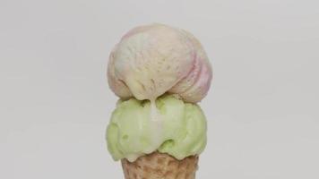 Time lapse, Close up, Melting two of ice cream on a waffle cone. Water flow from melting ice cream. On the white background. video