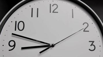 lasso di tempo, orologio da parete bianco, la lancetta corta indica il numero nove. il tempo è passato in fretta. sullo sfondo nero. video