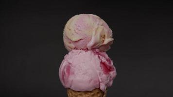 de cerca, derritiendo dos sabores de helado en un cono de galleta. el helado fluye después de que se ha derretido. sobre el fondo negro. video