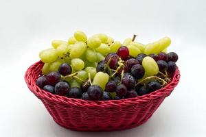 Fresh Red and White Grapes in a red basket isolated on white background. photo