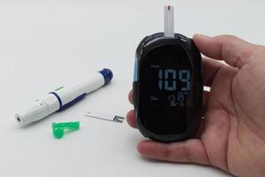 Woman with diabetes using glucometer, lancet pen and test strip on background. Diagnosis of diabetes concept photo