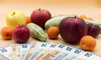 Fruits and vegetables and a pile of Euro banknotes. Fruits and vegetables cost concept photo